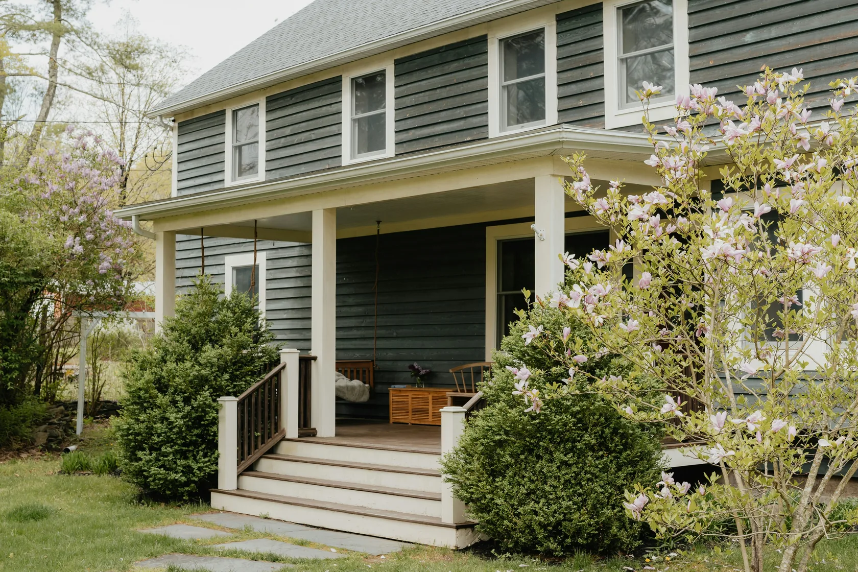 A two-story rental home with a covered front porch and a porch swing